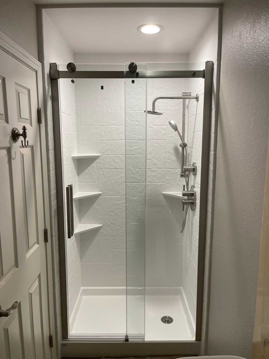 Shower with new tile-look walls and glass door, after