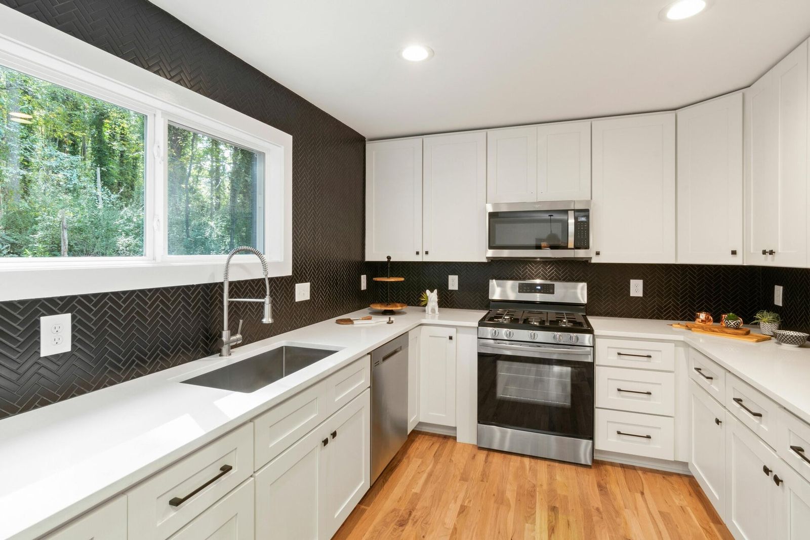 White kitchen with dark tile backsplash and stainless appliances